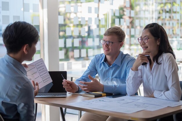 Groep jonge aziatische creatieve mensen Ontwerpers van mobiele applicaties en website-ontwerpers brainstormen en plannen projectwerk samen