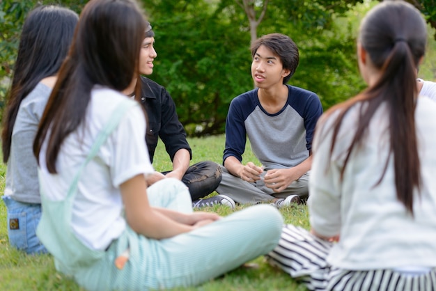 Groep jonge Aziatische vrienden die en samen in het park buiten hangen ontspannen