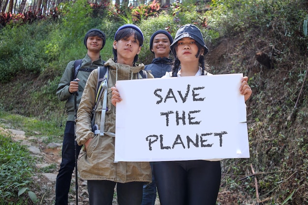 Groep jonge Aziatische vrienden die naar de camera kijken terwijl ze een wit bord met de tekst Save The Planet vasthouden