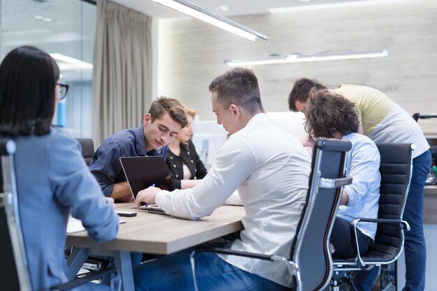 Groep jonge bedrijfsmensen die businessplan bespreken bij de moderne startbureaubouw