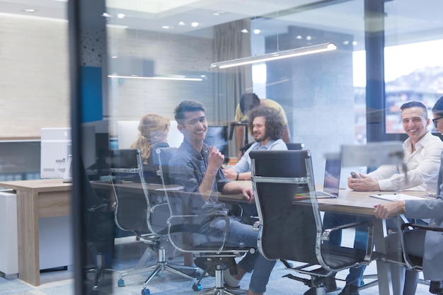 Groep jonge bedrijfsmensen die businessplan bespreken bij de moderne startbureaubouw