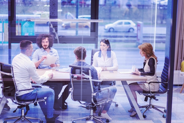 Groep jonge bedrijfsmensen die businessplan bespreken bij de moderne startbureaubouw