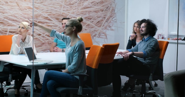 Groep jonge bedrijfsmensen die businessplan bespreken bij de moderne startbureaubouw