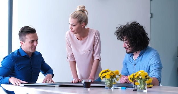 Groep jonge bedrijfsmensen die businessplan bespreken bij de moderne startbureaubouw