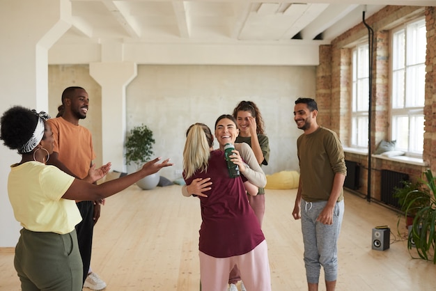 Groep jonge gelukkige mensen die elkaar begroeten en praten terwijl ze in de dansstudio staan