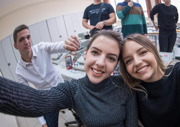 groep jonge gelukkige studenten die een selfie maken met een smartphone na een geslaagde dag in de elektronicaklas