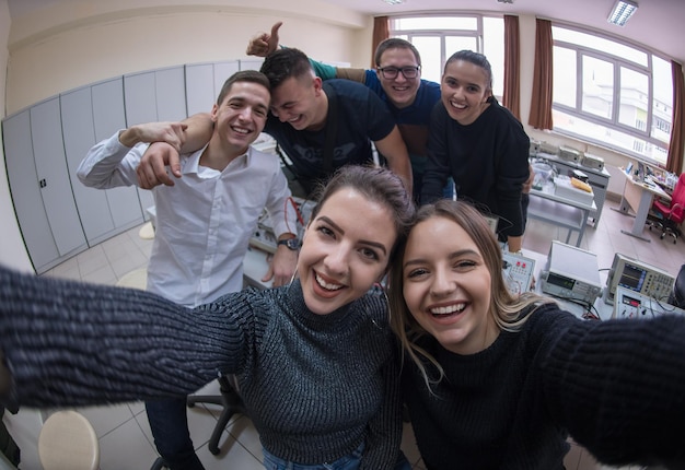 groep jonge gelukkige studenten die een selfie maken met een smartphone na een geslaagde dag in de elektronicaklas