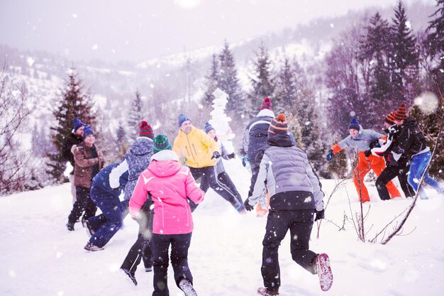 groep jonge gelukkige zakenmensen die plezier hebben terwijl ze genieten van een besneeuwde winterdag met sneeuwvlokken om hen heen tijdens een teambuilding in het bergbos