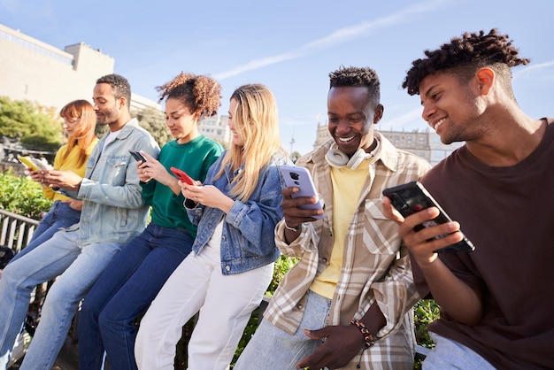 Groep jonge gemengde rassen met mobiele telefoons opgewonden studenten met behulp van technologische apparaten