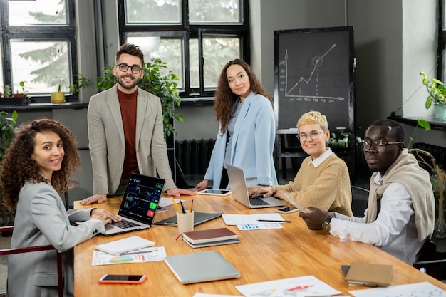 Groep jonge interculturele financiers verzameld aan tafel in kantoor