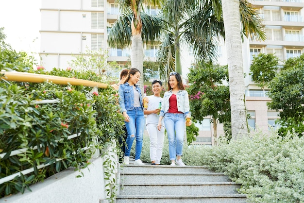 Groep jonge mannen en vrouwen die buiten de trap aflopen, praten en frisdrank drinken