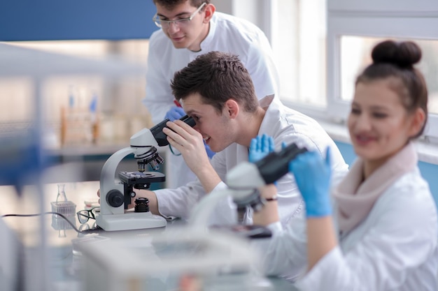 Groep jonge medische studenten die samen onderzoek doen in het scheikundelaboratorium, teamwork door student binnenshuis