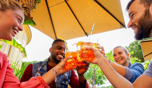 Groep jonge mensen die plezier hebben buiten in een bar met drankjes in de zomer - Vrienden juichen met coktail en lachend lachend met elkaar