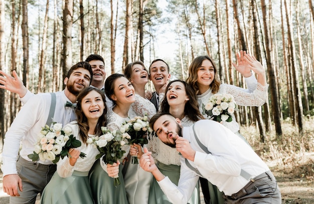 Groep jonge mensen die stevig knuffelen en vrolijk lachen, een groep vrienden die een trouwdag vieren, mooie vriendelijke familie, getuigen en getuigen op de bruiloft
