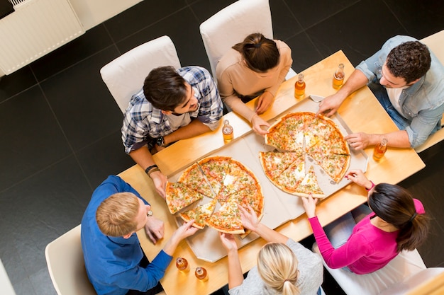 Groep jonge mensen pizza eten en cider drinken