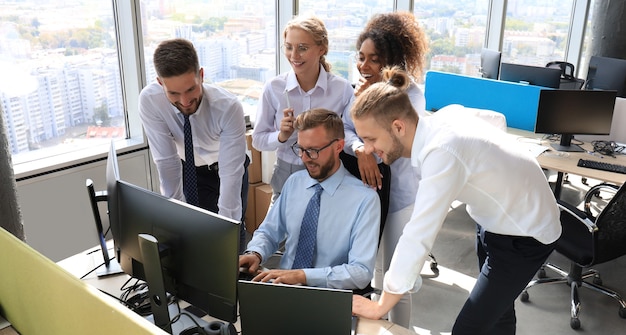 Groep jonge moderne mensen in formalwear die moderne technologieën gebruikt terwijl ze in het creatieve kantoor werken.