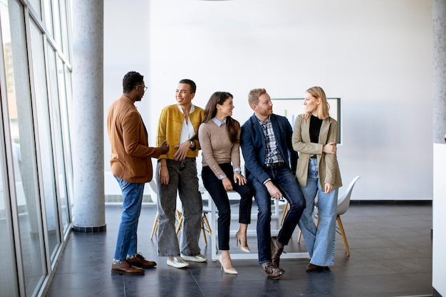 Groep jonge positieve zakenmensen die samen op kantoor staan