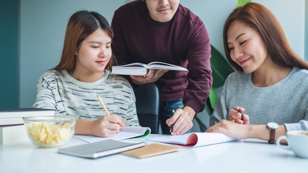 Groep jonge studenten die bijles geven en een werkboek inhalen met vrienden