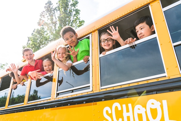 Groep jonge studenten die naar de basisschool gaan in een gele schoolbus - Basisschoolkinderen hebben plezier