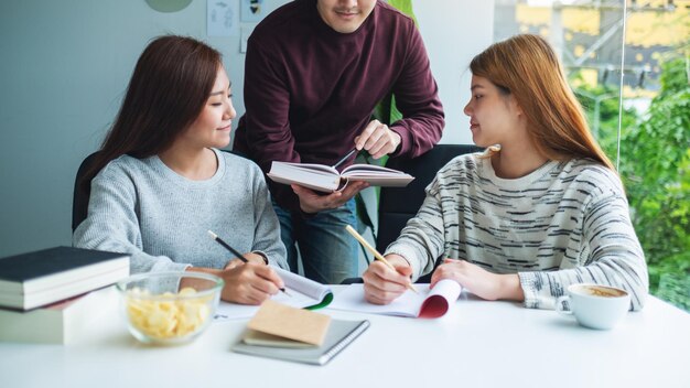 Groep jonge studenten die samen bijles geven en werkboek inhalen