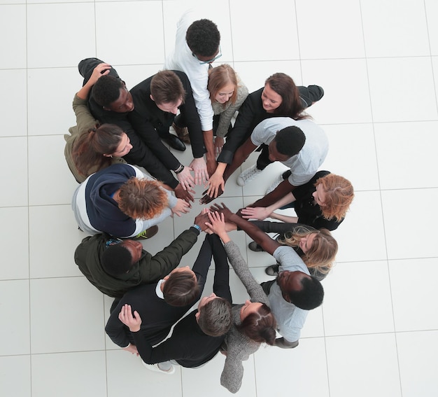 Groep jonge succesvolle mensen staat samen rond handen