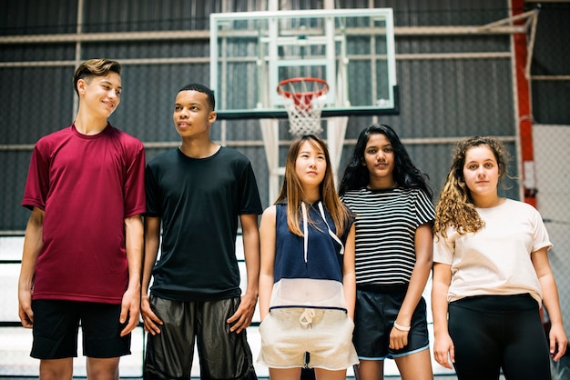 Groep jonge tienervrienden op een basketbalhof die zich op een rij bevinden