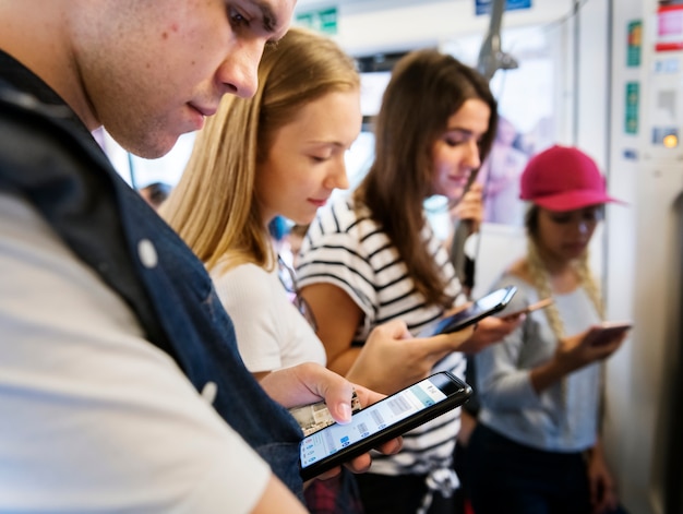 Groep jonge volwassen vrienden die smartphones in de metro gebruiken