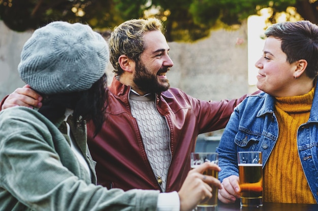 Foto groep jonge vrienden die elkaar ontmoeten op het terras en samen bier drinken