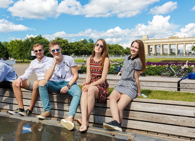 Groep jonge vrienden die op een parkbank zitten te praten.