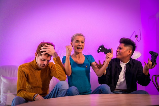 Groep jonge vrienden die samen videogames spelen op de bank thuis, paarse led-vrouw die wint