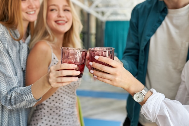 Groep jonge vrienden rammelende glazen met dranken in café