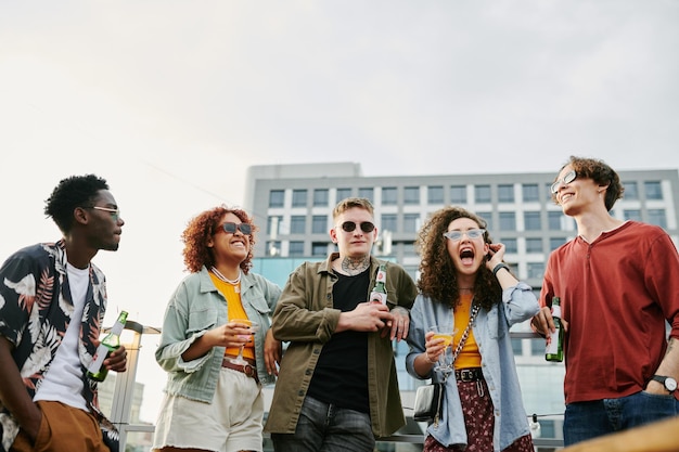 Groep jonge vrolijke multiculturele vrienden in vrijetijdskleding met drankjes