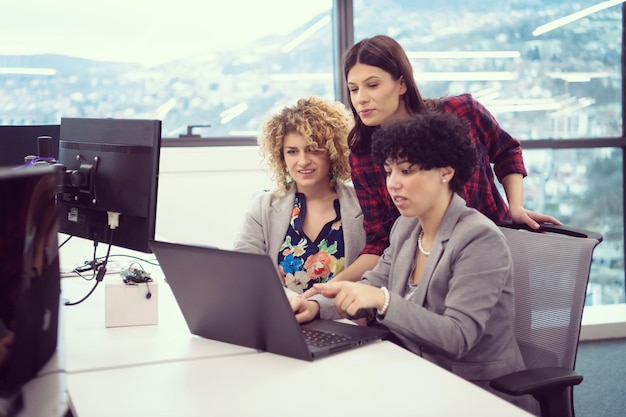 groep jonge vrouwelijke softwareontwikkelaars die laptopcomputer gebruiken tijdens het schrijven van programmeercode bij modern creatief opstartkantoor