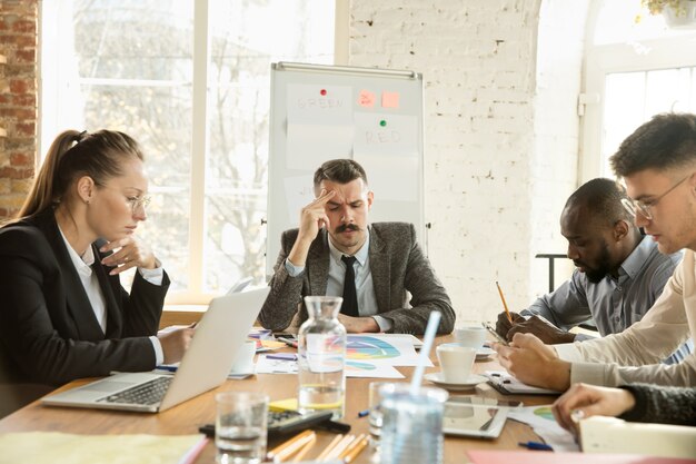 Groep jonge zakelijke professionals die een vergadering hebben. diverse groep collega's bespreken nieuwe beslissingen, toekomstplannen en strategie. creatieve vergadering en werkplek, zaken, financiën, teamwork.