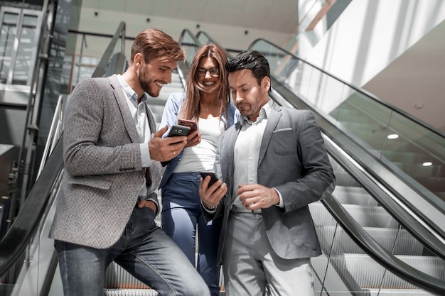 Groep jonge zakenlieden die naar de schermen van hun smartphones bedrijfsconcept kijken