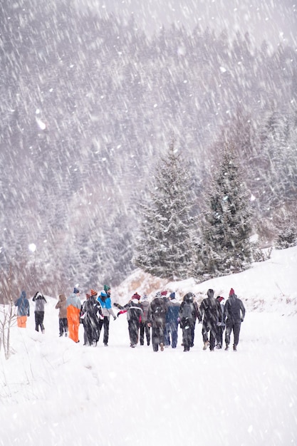 groep jonge zakenmensen wandelen door een prachtig winterlandschap met sneeuwvlokken om hen heen tijdens een teambuilding in het bergbos
