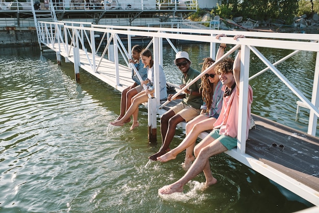 Groep jonge zorgeloze vrienden ontspannen op de brug en opspattend water