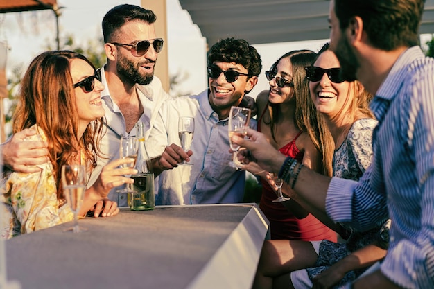 Groep jongeren die een leuk feestje hebben en samen champagne drinken terwijl ze in de tuin staan - vrienden die mousserende wijn roosteren