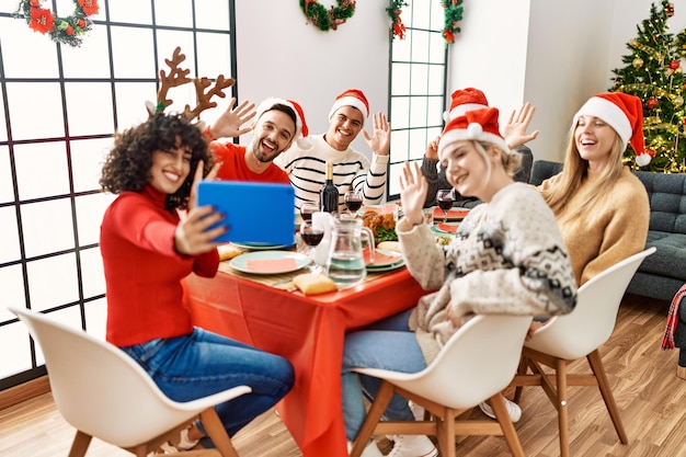 Groep jongeren die kerstdiner en videogesprek hebben met touchpad thuis.