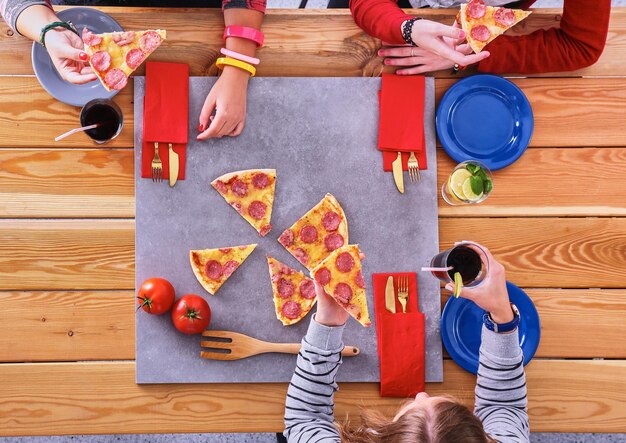 Groep jongeren die pizza eten bij bureau.