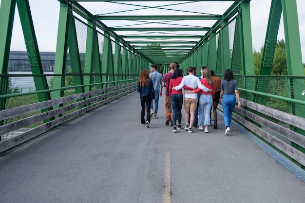 Groep jongeren die rug aan rug en samen een brug oversteken
