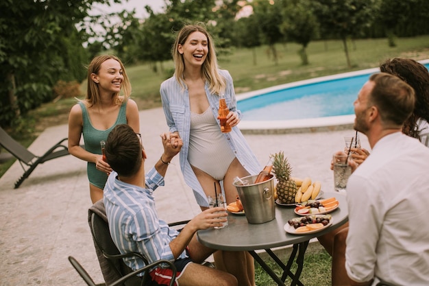 Groep jongeren juichen met cider bij het zwembad in de tuin