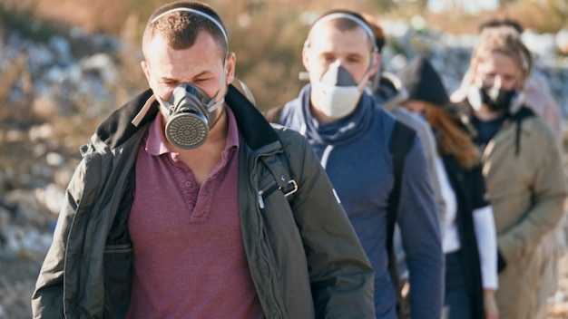 Foto groep jongeren met gasmaskers die door de giftige rook gaan in een vuilnisbelt waar mensen om geven...