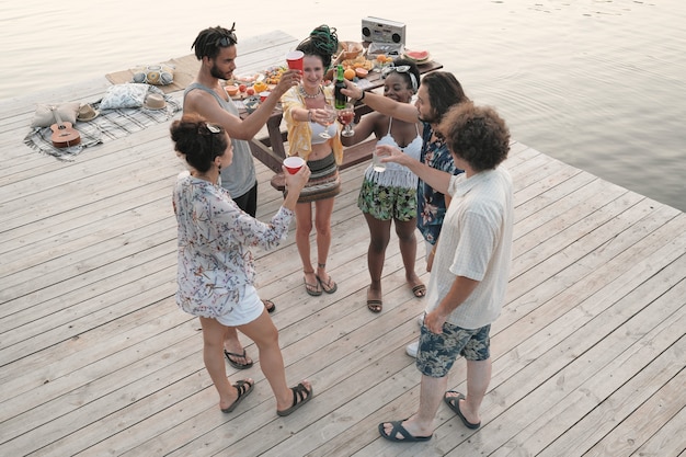 Groep jongeren roosteren met cocktails en bier en samen vieren op een feestje op een pier