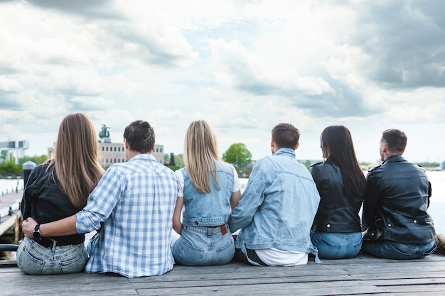 Groep jongeren zittend op een pier naast een rivier