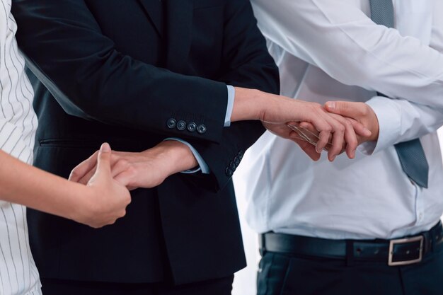 Groep kantoorpersoneel hand in hand om de harmonie op de werkplek te bevorderen