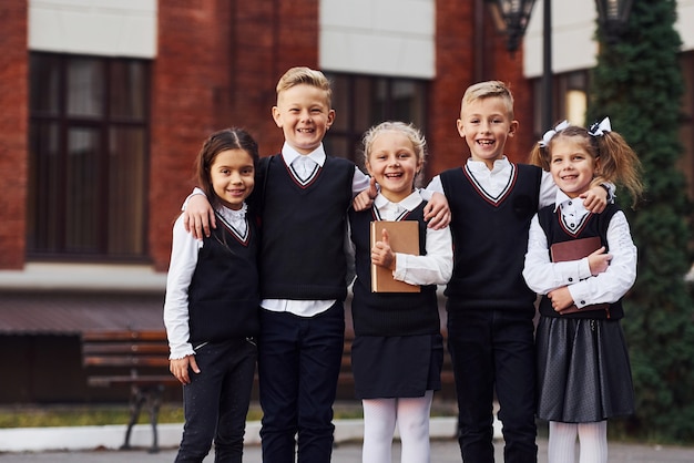 Groep kinderen in schooluniform dat buiten samen is in de buurt van het onderwijsgebouw.