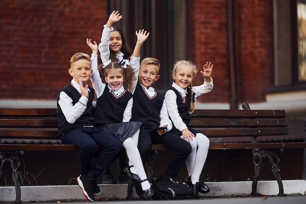 Groep kinderen in schooluniform dat buiten samen is in de buurt van het onderwijsgebouw.