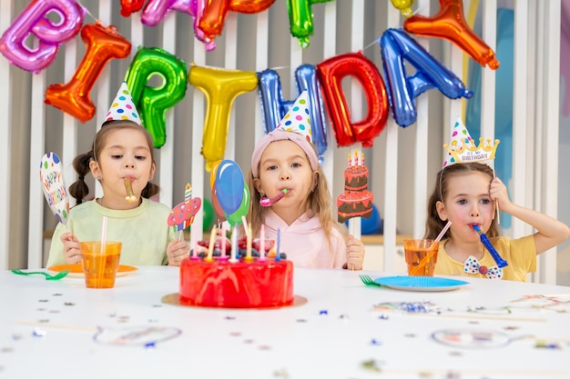 Groep kinderen met pijpen grappige inscripties en maskers hebben plezier op een verjaardagsfeestje