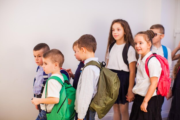 Groep klasgenoten die samen naar lessen gaan Gelukkige kinderen met rugzakken op school